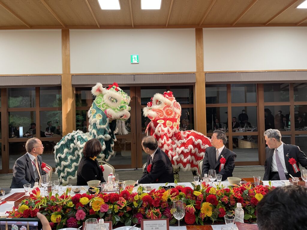 栗林公園 商工奨励館（讃岐迎賓館）で開催された中華人民共和国 孔鉉佑大使 歓迎レセプションの最中。ピンクとグリーンの色の中国獅子舞が二頭登場している。出席者が物珍しそうに見ている。
